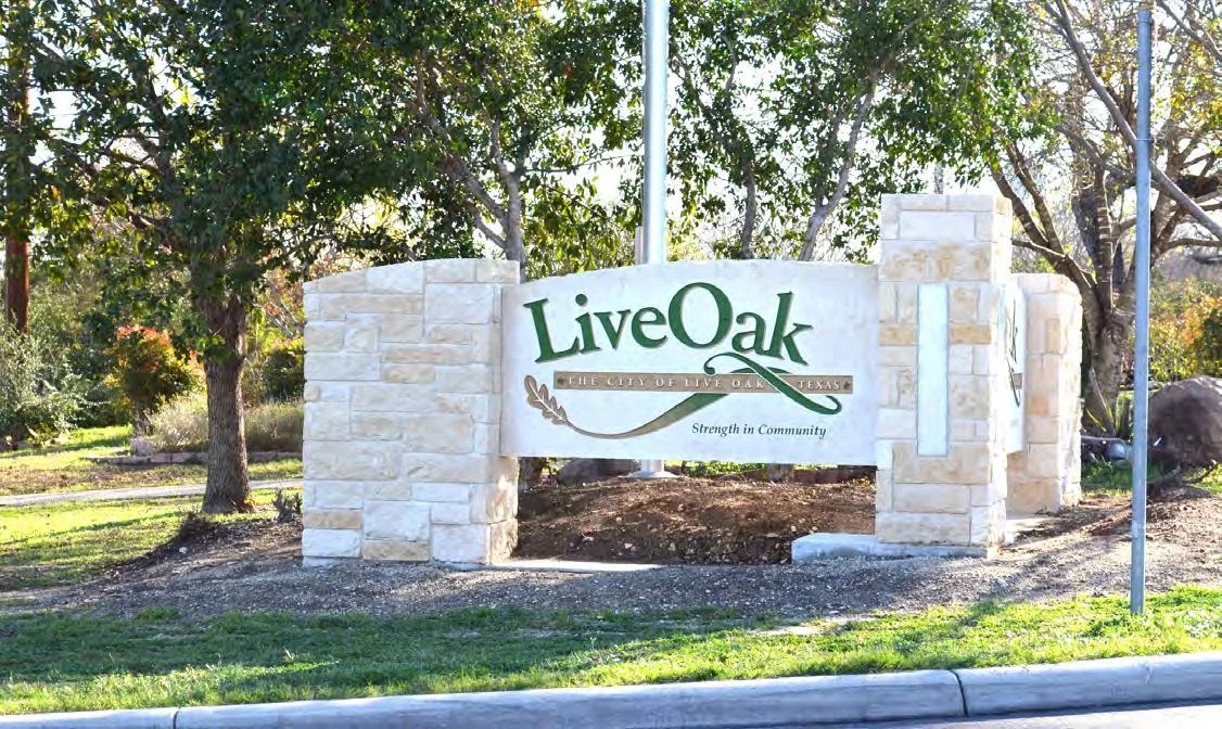 Live Oak entrance sign set in stone beneath leafy trees