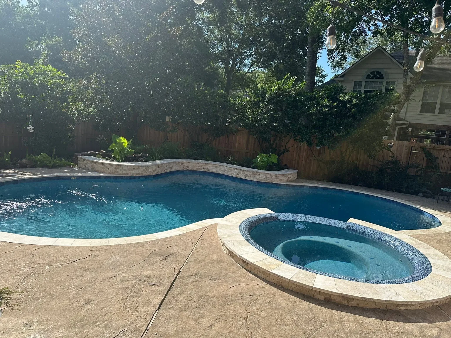 Pool and spa after renovation with pale coping and renewed mosaic tile